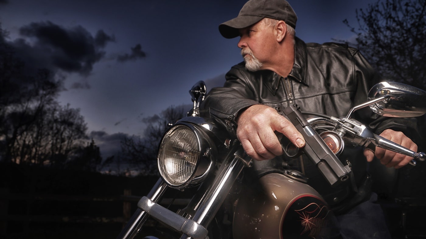 This photograph shows an older man riding a motorcycle at a dusk while lawfully carrying a pistol for self-defense. It captures the essence of shooting sports and target shooting among senior citizens who value firearm training. The image reflects the challenges and adaptations required for maintaining shooting skills, even when facing arthritis and reduced motor skills. It brings together elements of active shooter training and concealed carry practices, emphasizing safe action and proper grip. The subject’s confident posture is a testament to resilience and the commitment to self-protection. The scene is designed to inspire older adults to pursue shooting sports as a means of home defense and personal empowerment. Overall, it offers a comprehensive look at how fine motor skills and situational awareness remain vital at every stage of life.